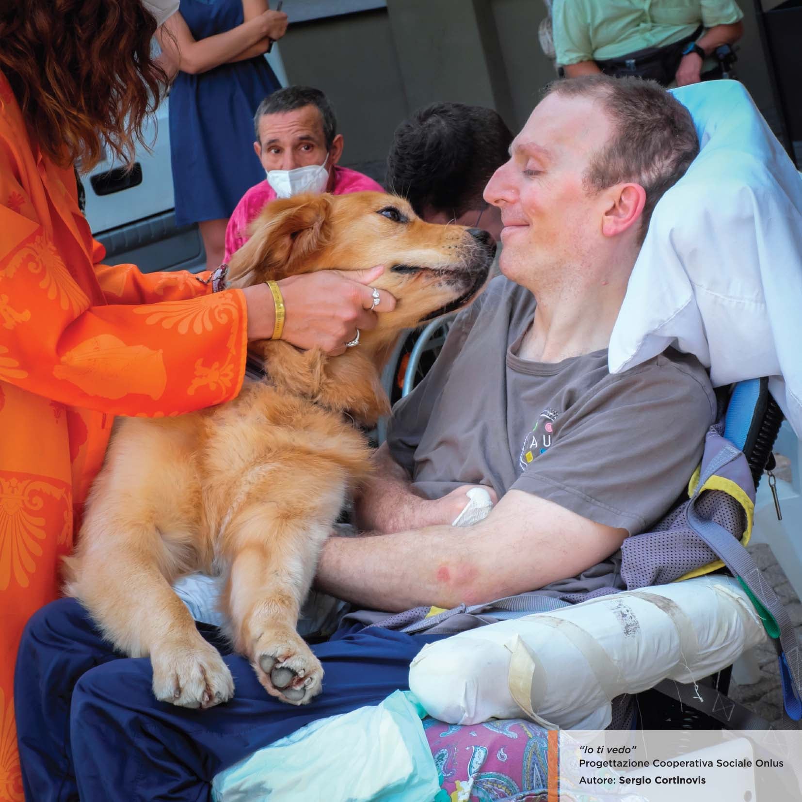 Un cane in braccio ad una persona disabile durante una sessione di pet therapy