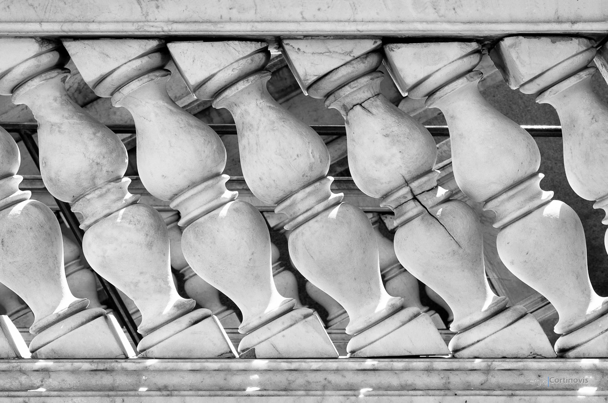 Una crepa in uno degli elementi in marmo del parapetto di una scalinata rompe il pattern di forme accarezzate dalla luce