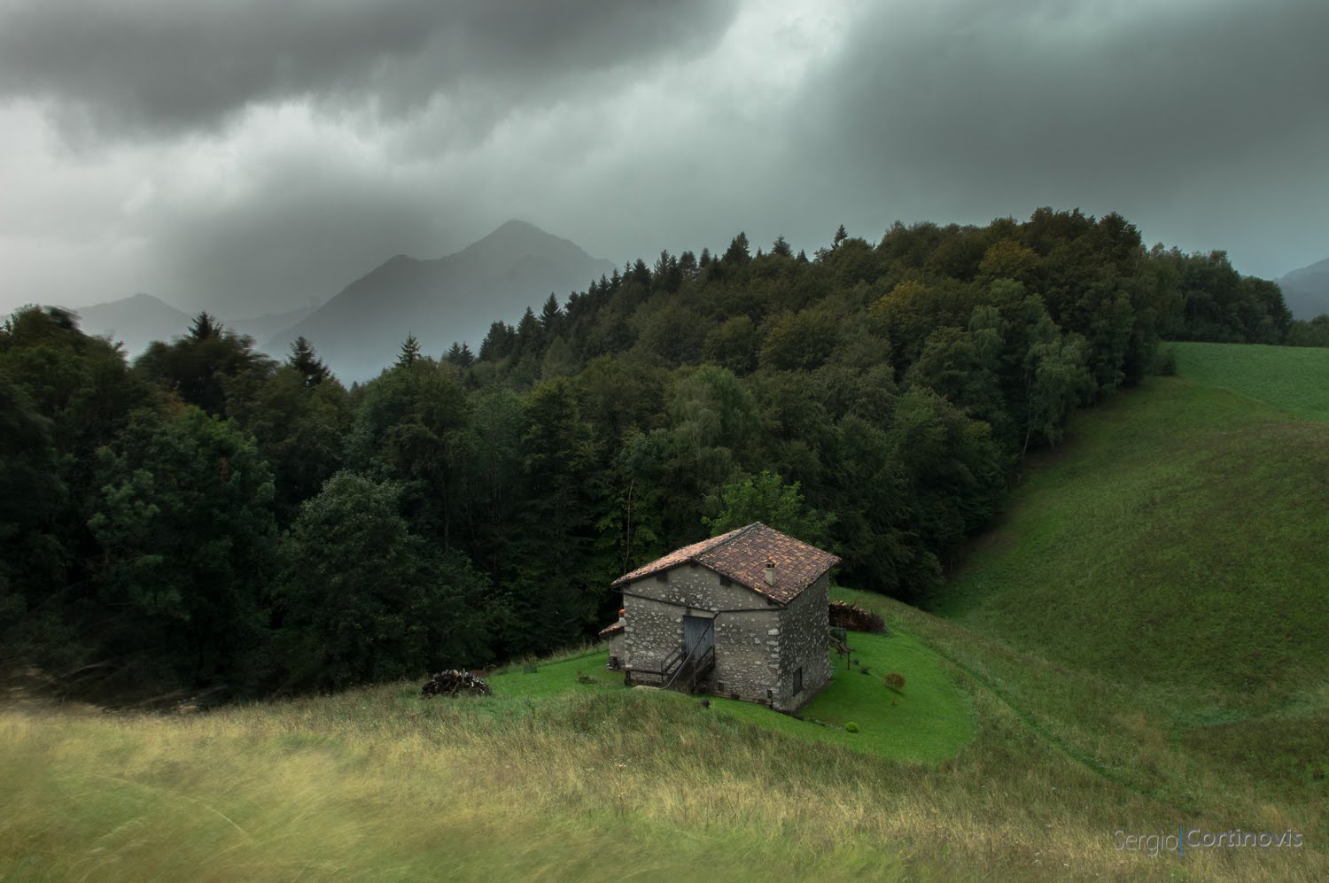 Temporale a Valpiana di Serina in Valle Brembana (Provincia di Bergamo). Cielo scuro sopra un prato e delle montagne